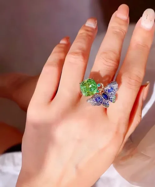 Bague cocktail papillon vert menthe et bleu portée au majeur