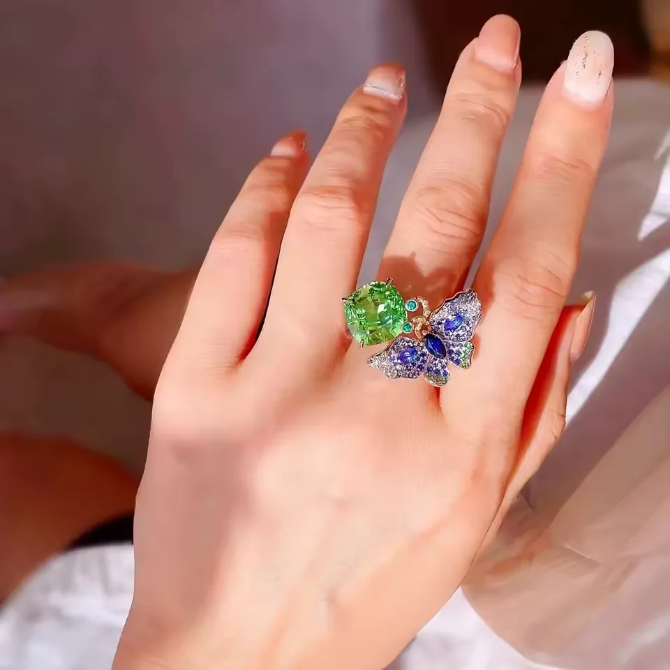 Bague cocktail papillon vert menthe et bleu portée au majeur