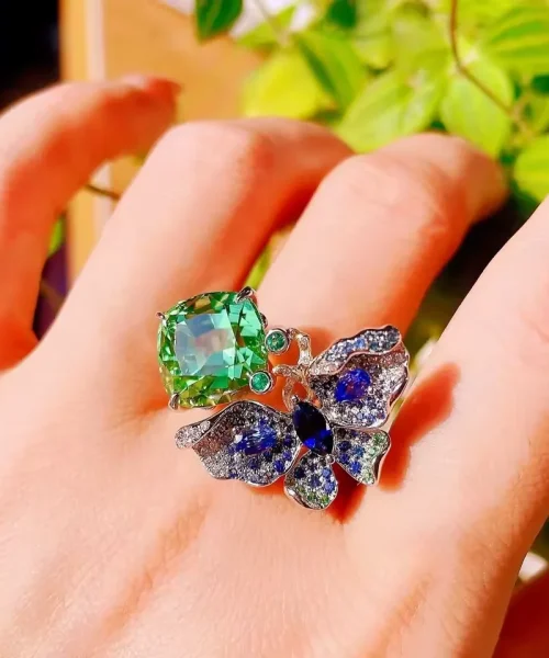 Bague cocktail papillon portée, grosse pierre vert menthe et papillon pavé de pierres bleues