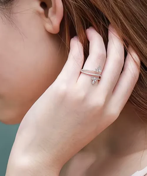 Bague papillon croisée portée au majeur, bandes pavées entrecroisées