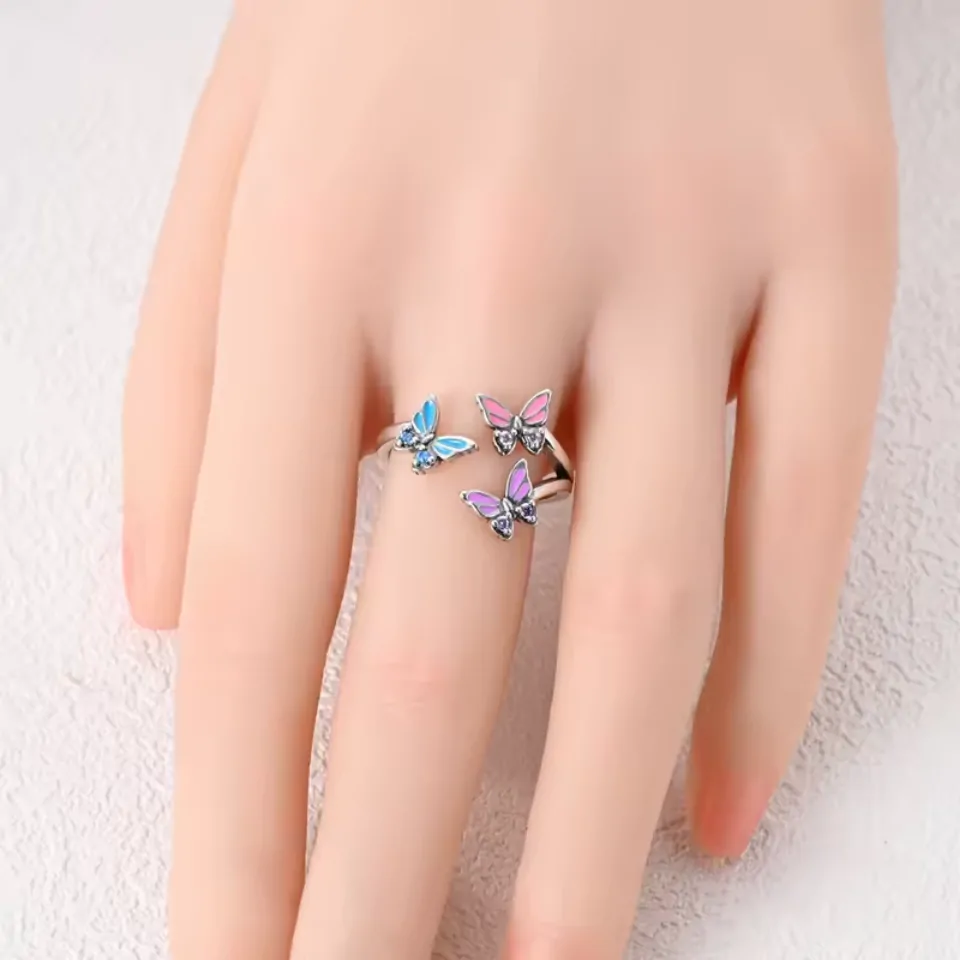 Bague trois papillons colorés portée au majeur