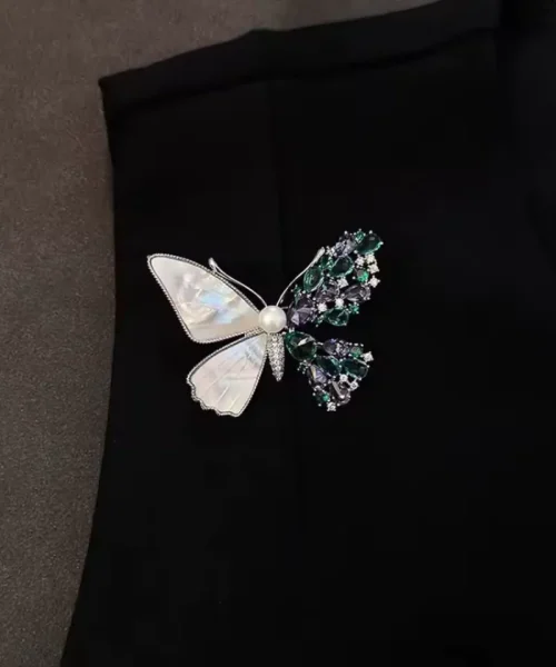 Broche papillon asymétrique portée sur une veste noire