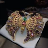 Broche papillon baroque, pierres roses et violettes, perles et strass sur monture dorée