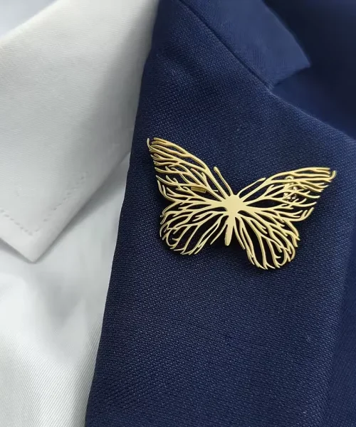 Broche papillon en or portée sur un revers de blazer marine