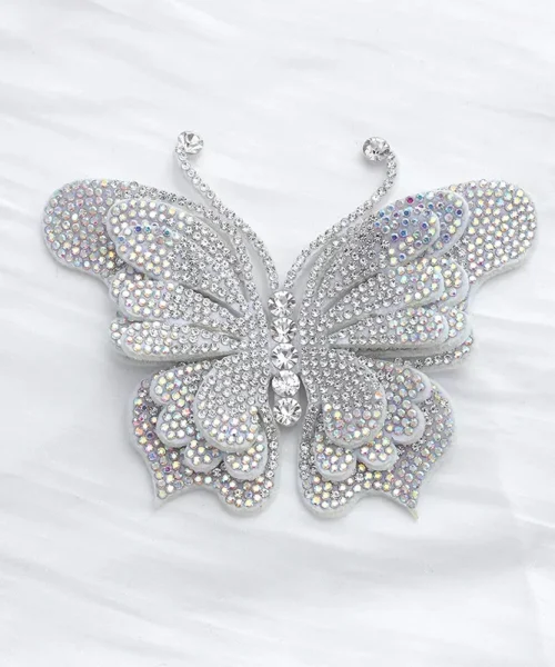 Broche papillon en relief blanc, ailes superposées couvertes de strass