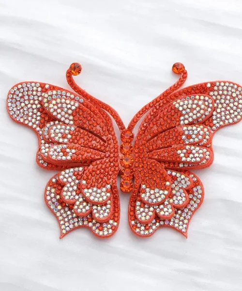 Broche papillon en relief orange, ailes superposées couvertes de strass