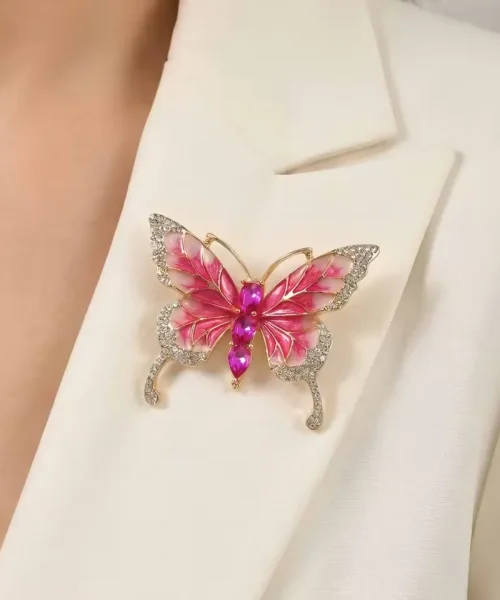 Broche papillon rose portée sur le revers d'une veste crème