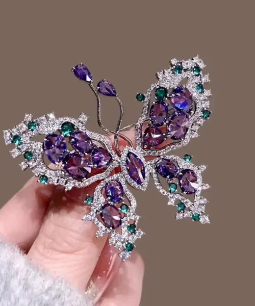 Broche papillon violette tenue en main, pierres violettes et vertes
