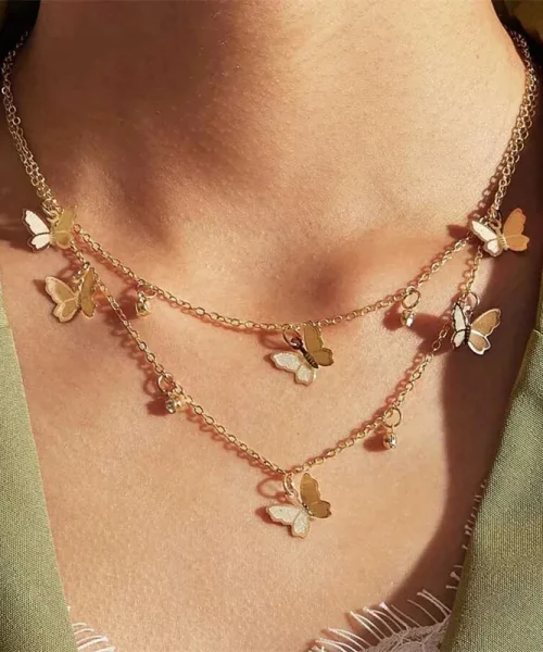 Collier breloques papillon doré porté sur un décolleté, deux rangs superposés