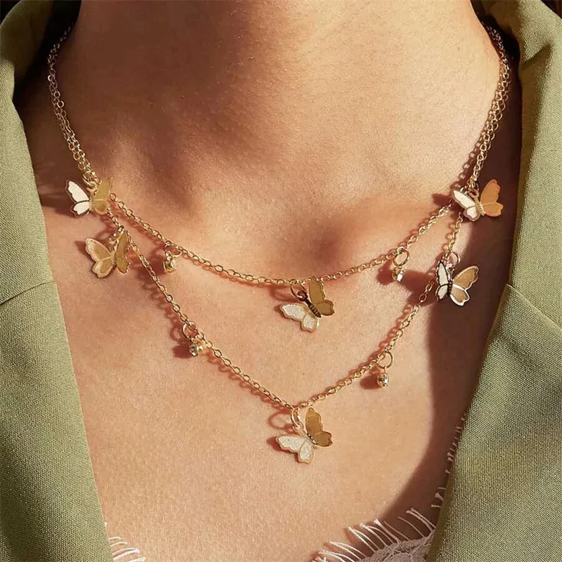 Collier breloques papillon doré porté sur un décolleté, deux rangs superposés