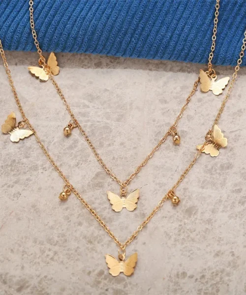 Collier à breloques papillon doré posé à plat, chaîne courte et chaîne longue