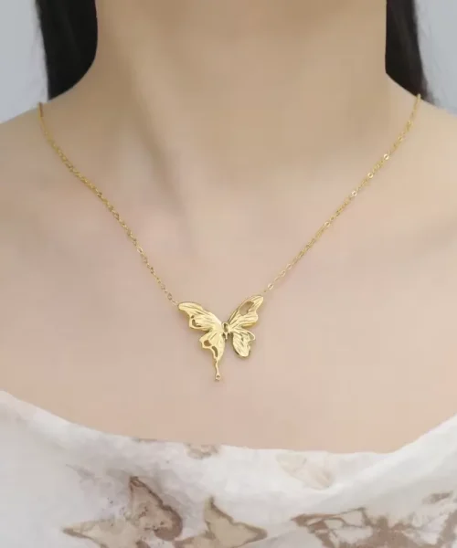 Collier papillon fondu doré porté au creux des clavicules