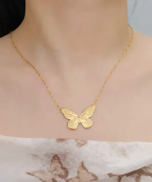 Collier papillon monarque doré porté sous les clavicules