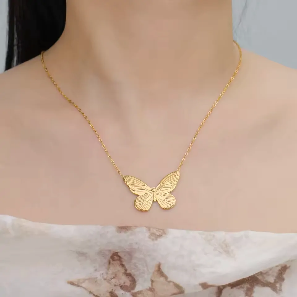 Collier papillon monarque doré porté sous les clavicules