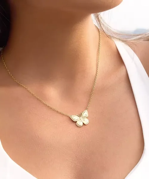 Collier papillon plaqué or porté sur un décolleté en V