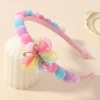Serre-tête papillon arc-en-ciel pour petite fille, pompons pastel et arceau satiné rose