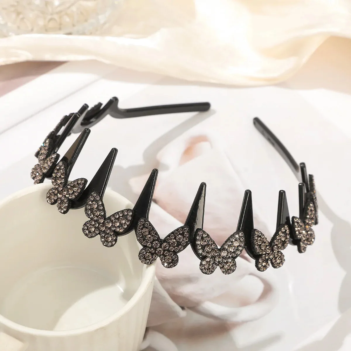 Serre-tête papillon strass gris, arceau ondulé à dents noir couronné de papillons pavés